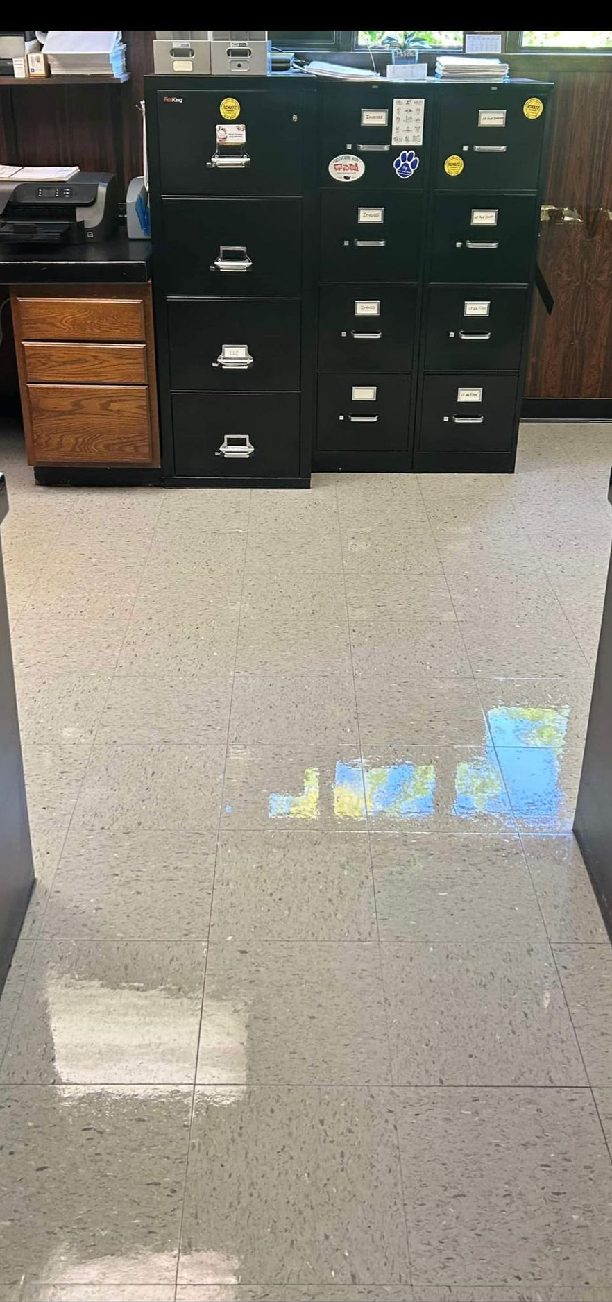 Black file cabinets in an office. Beige floor reflects light.
