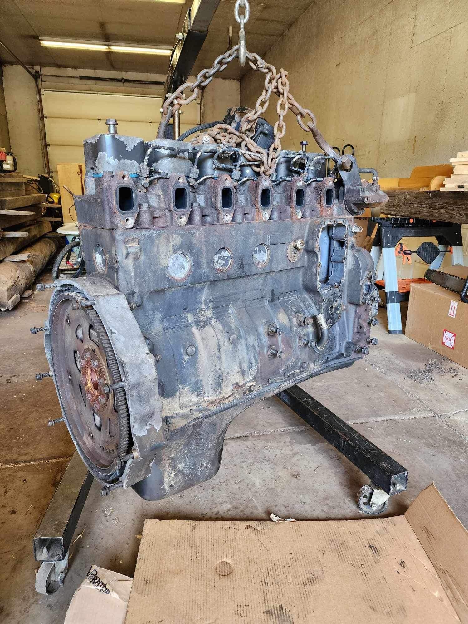 Diesel engine suspended from a hoist, in a workshop.