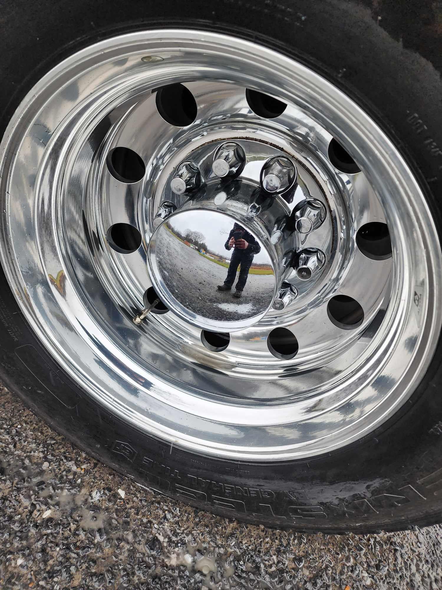 Shiny chrome truck wheel with tire, hubcap, and black rim.