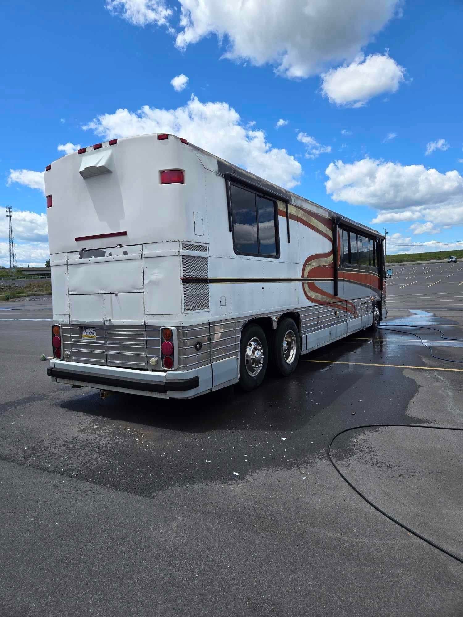 White RV with brown and orange accents parked on pavement under a blue sky.