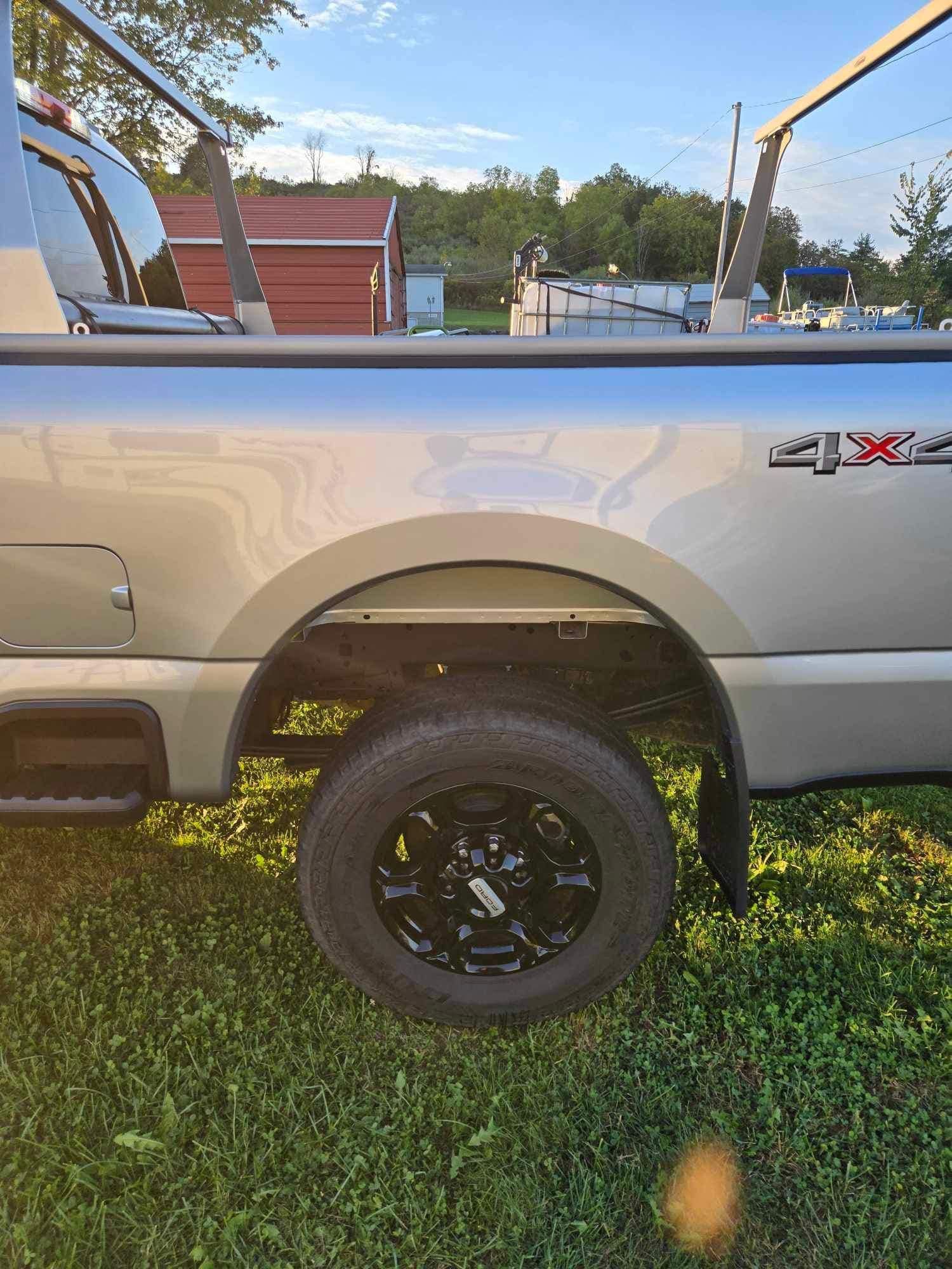 Tan pickup truck with black wheels, 4X4 logo, parked on grass in daytime.