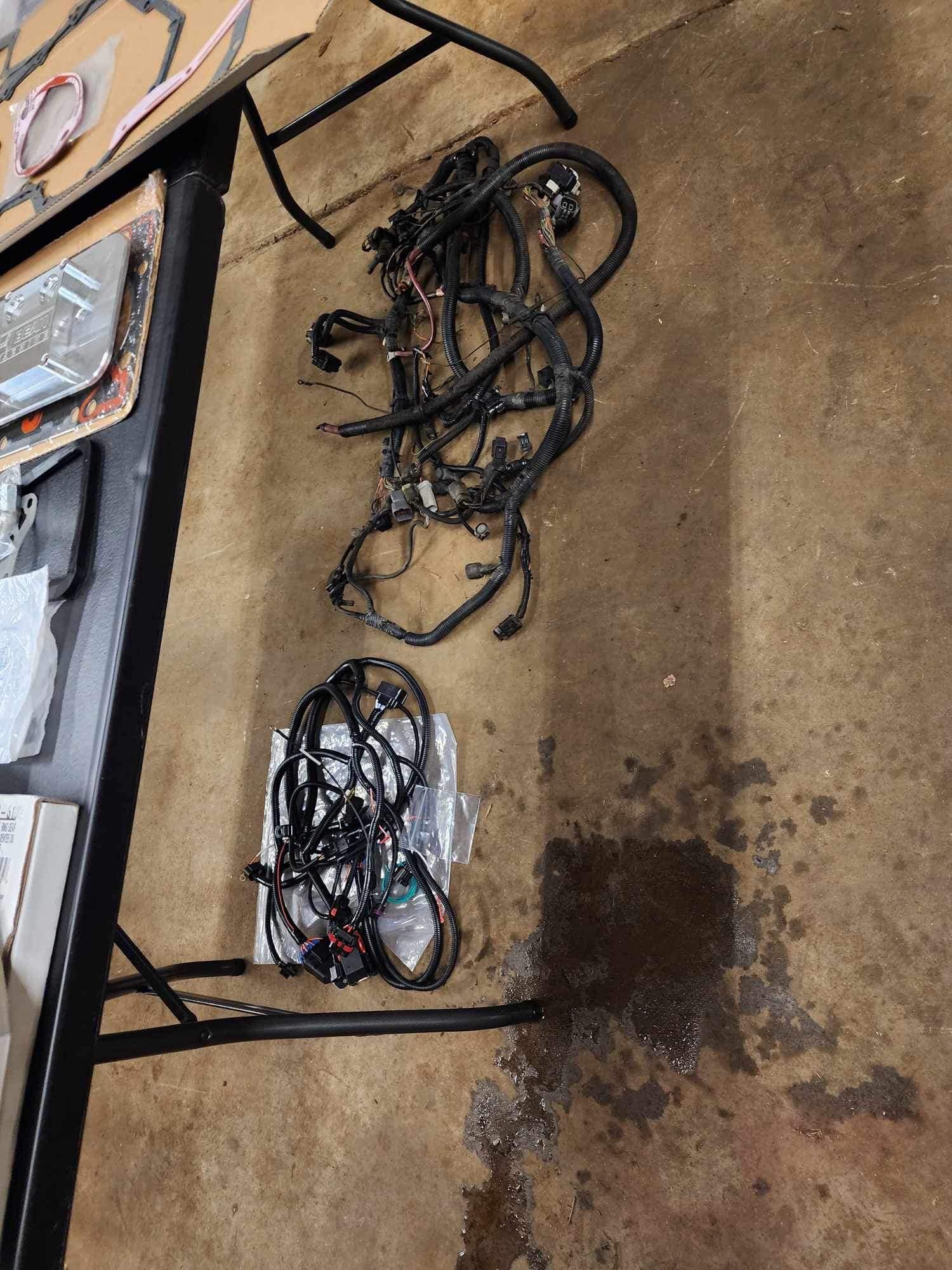 Black wires and cables on a table and on the floor, likely automotive wiring harnesses.