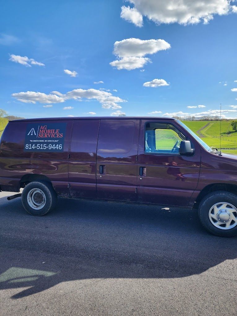 Maroon van with company logo parked on asphalt under a blue sky with clouds.