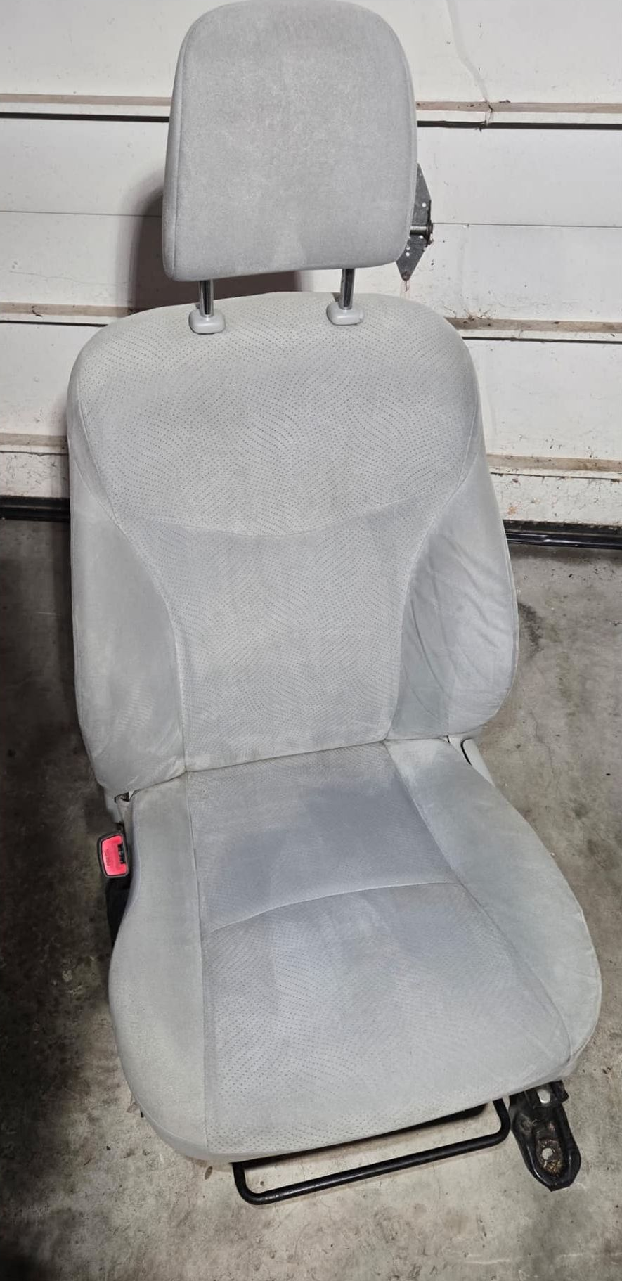 Light gray car seat with a headrest, set against a plain background.