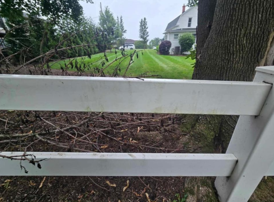 White fence with a grassy lawn and house in the background.