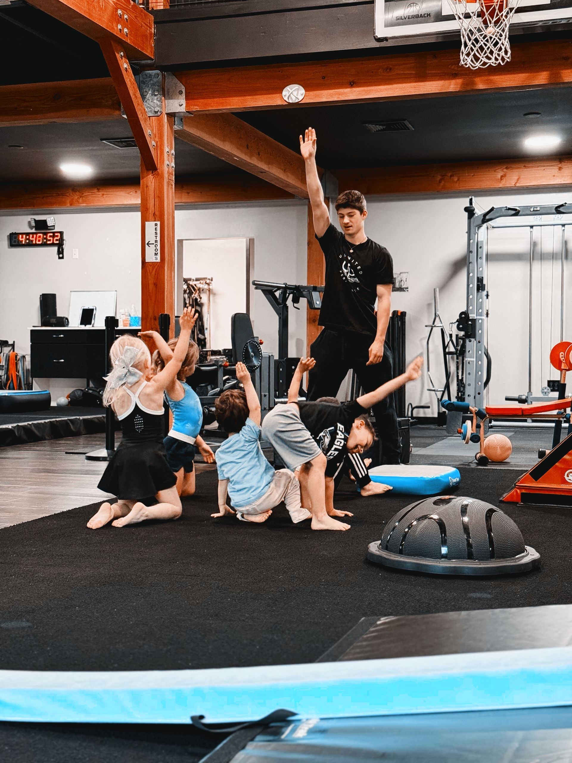 Group stretching in a gym in Gibbsboro, NJ, with one person raising an arm beside exercise equipment.