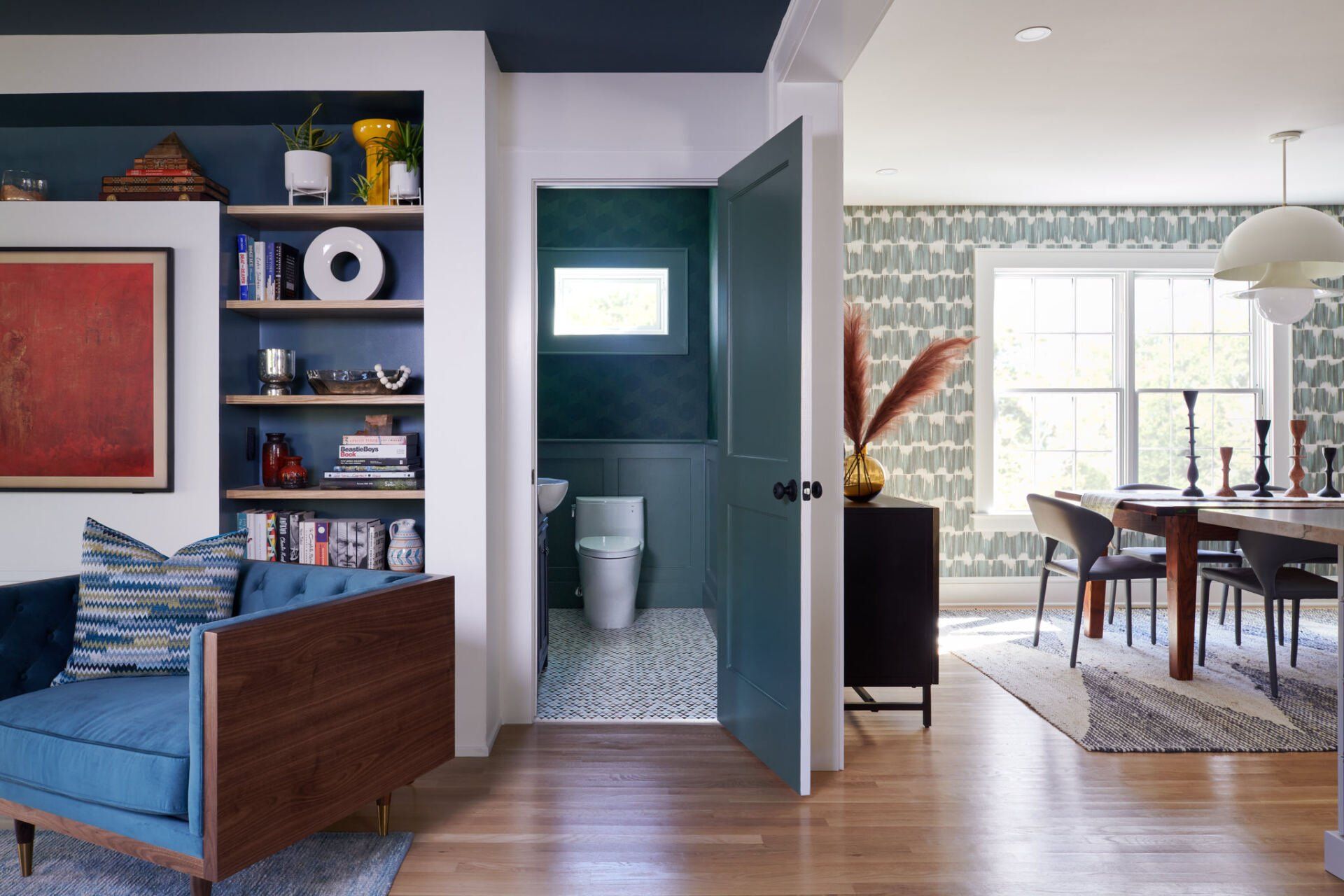 A living room with a blue chair and a blue door leading to a bathroom.