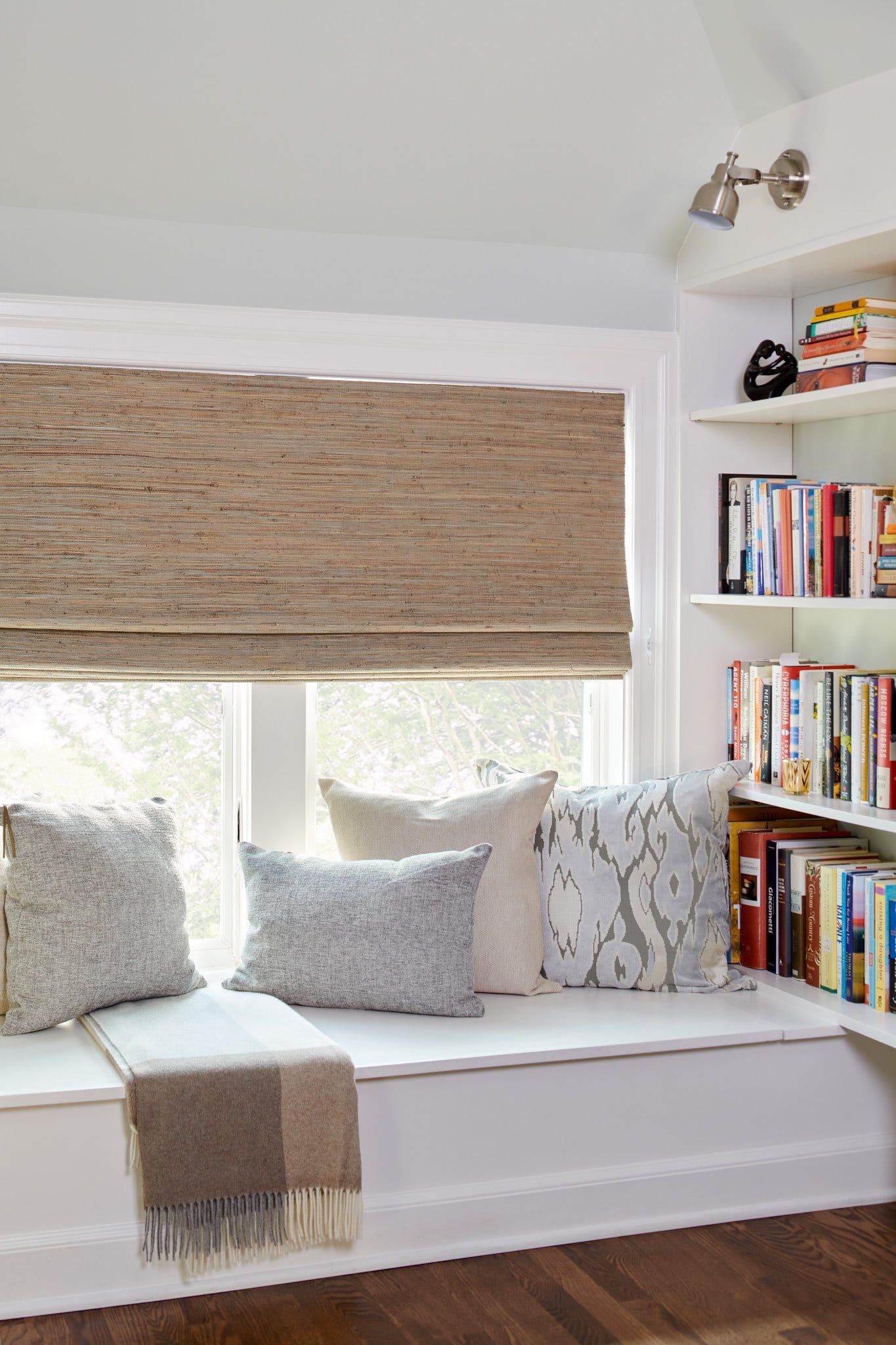 A living room with a window seat and a bookshelf filled with books.