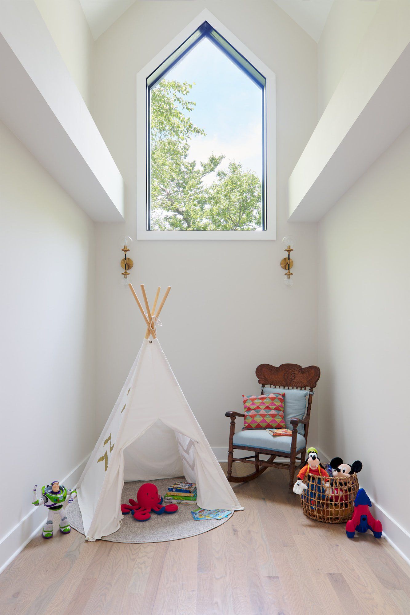A child 's room with a teepee , rocking chair , and toys.