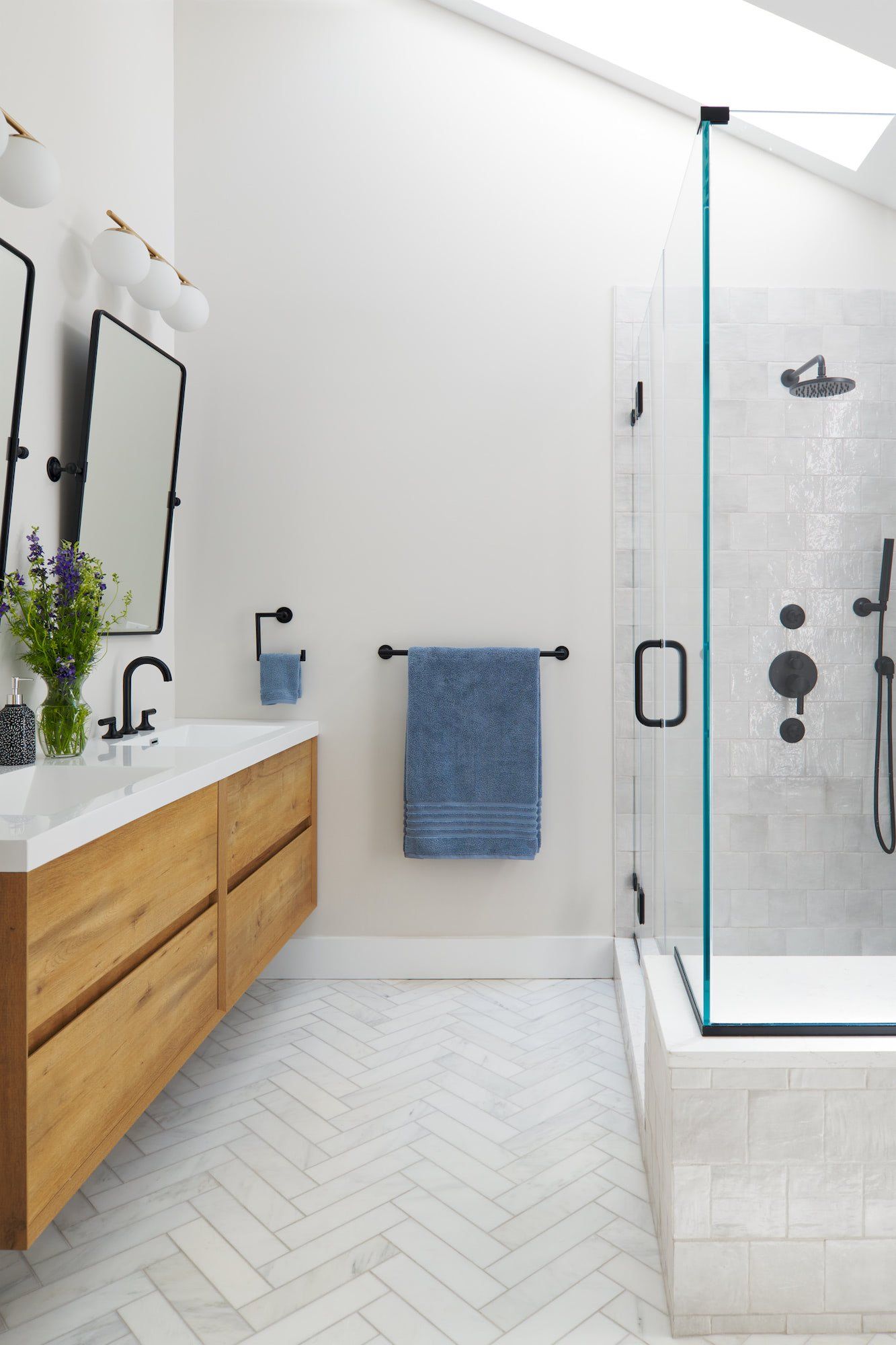 A bathroom with a walk in shower , sink and mirror.