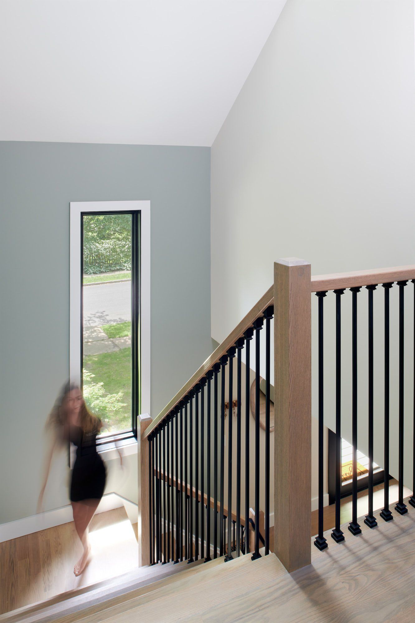 A woman is walking down a set of stairs in a house.