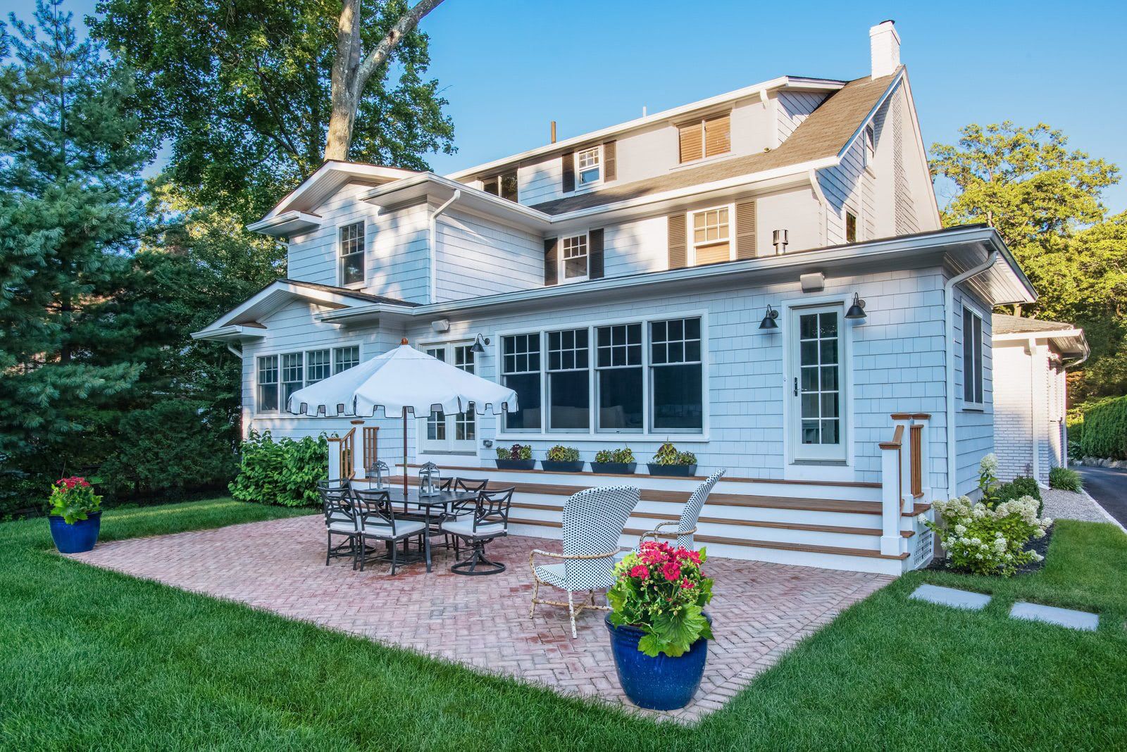 A large white house with a patio and umbrellas in front of it.