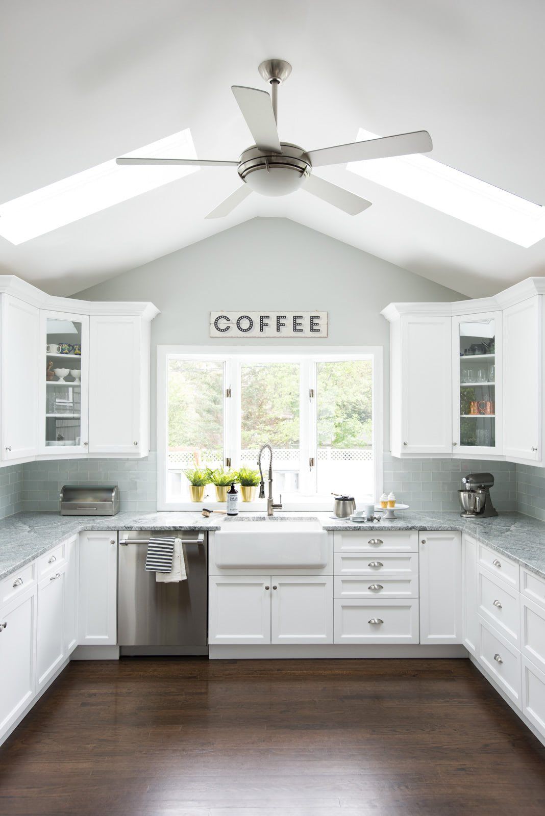 A kitchen with white cabinets , stainless steel appliances , and a ceiling fan.