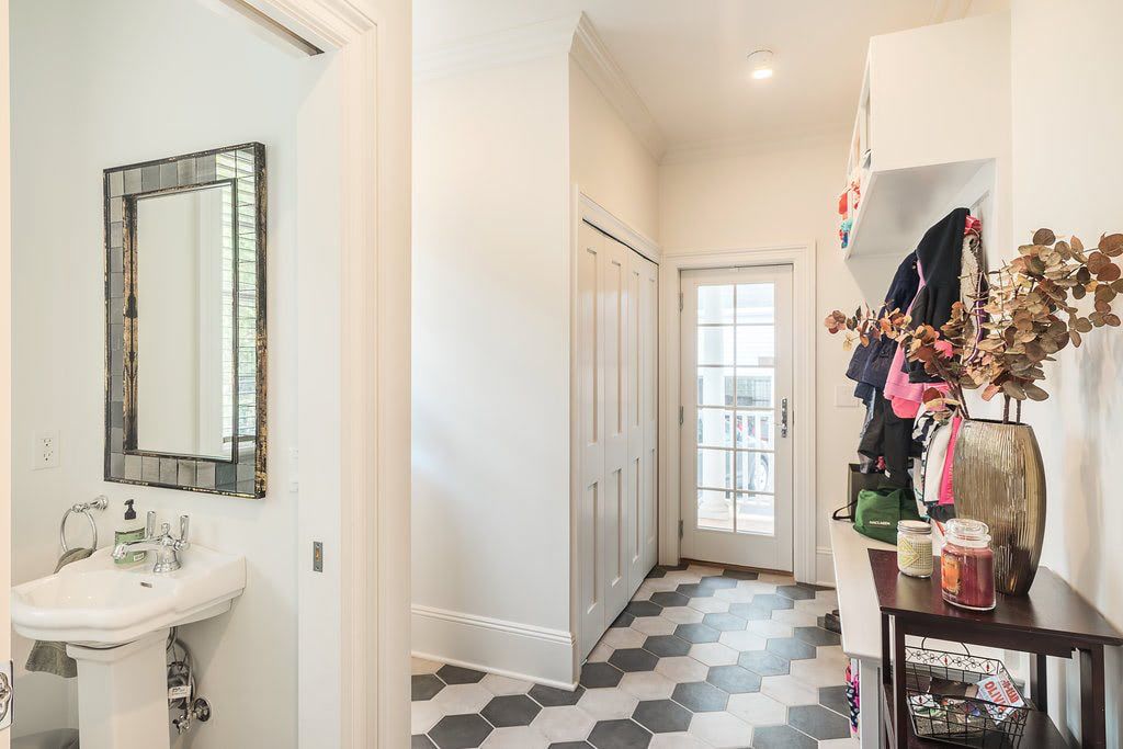 A bathroom with a sink , mirror , and checkered floor.