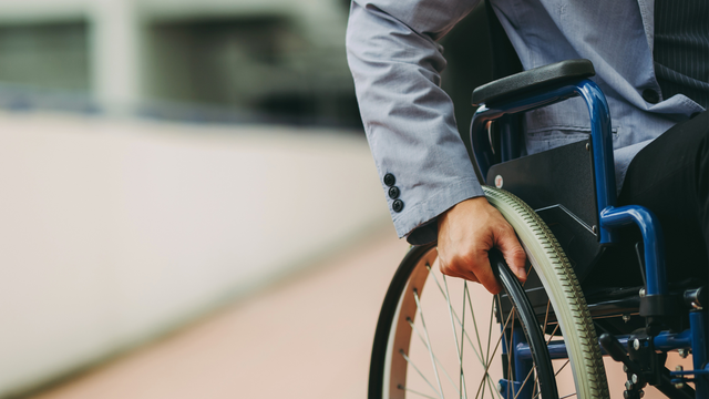 A man in a suit is sitting in a wheelchair.
