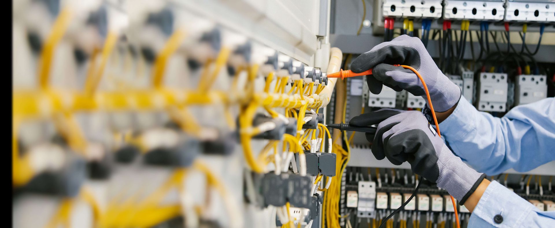 An electrician is working on an electrical panel in a factory.
