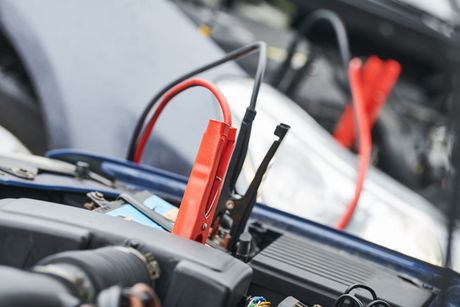 Car battery jumper cables connected to a vehicle's battery.