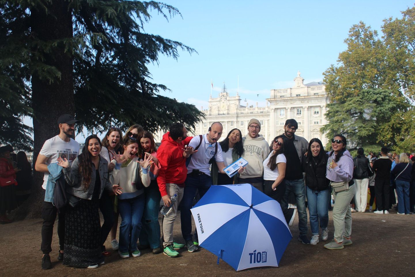 A cheerful group posing in front of Madrid’s Royal Palace, enjoying the vibrant atmosphere of a Madrid Free Walking Tour.