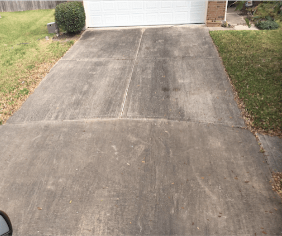A dirty concrete driveway leading to a white garage door.