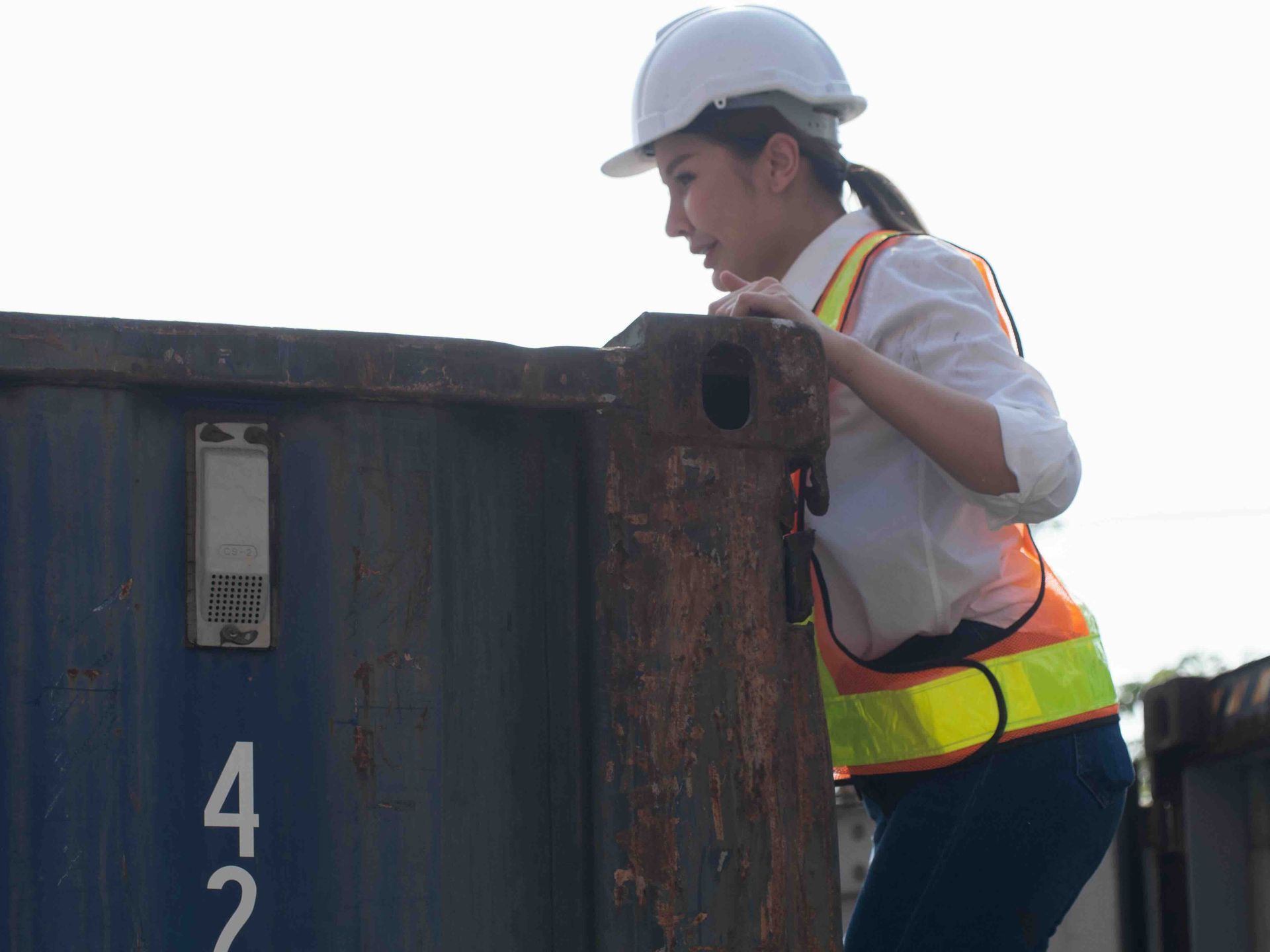 A photo of a woman looking into a dumpster rental full of construction debris.