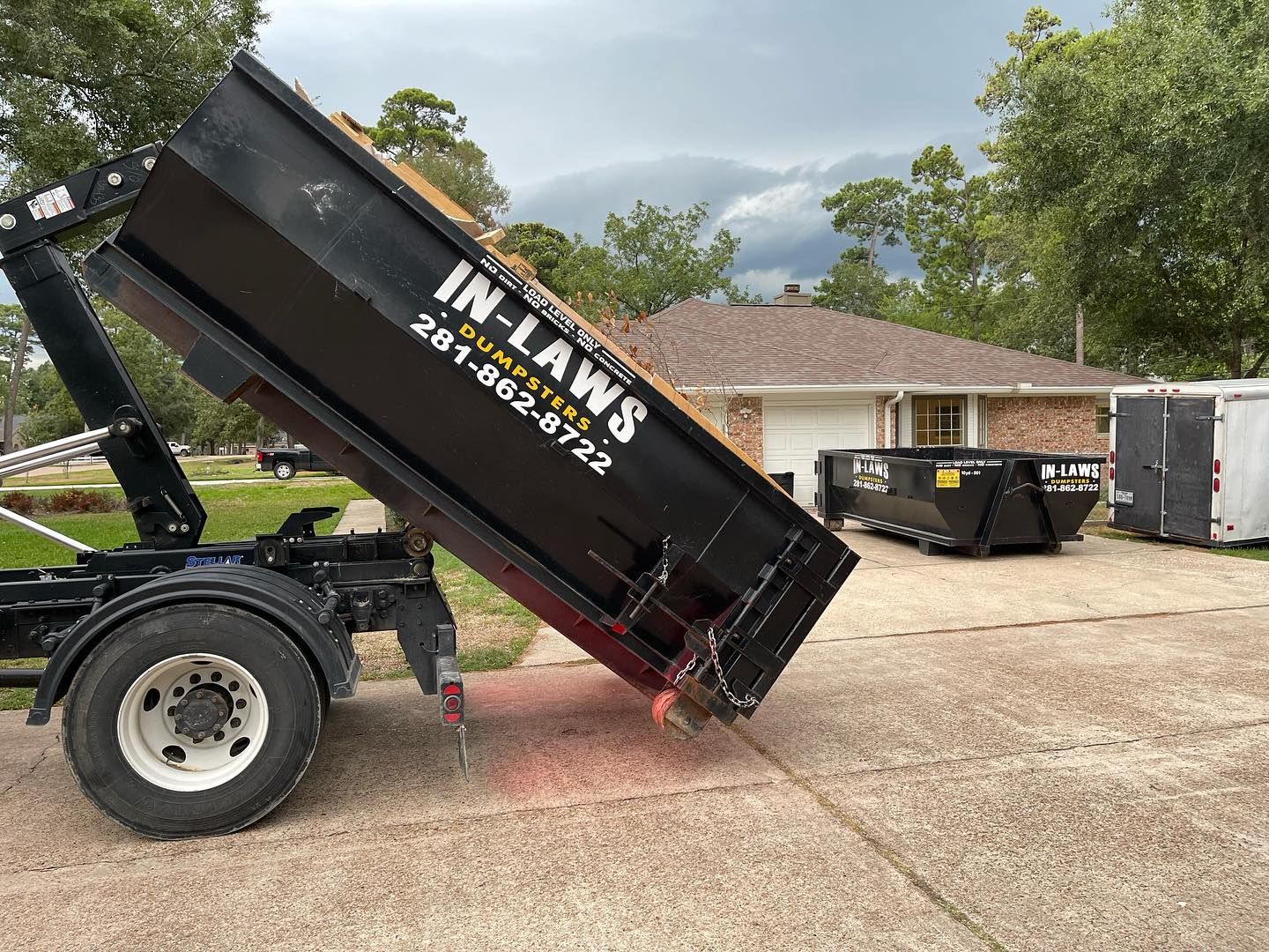 A dumpster is sitting in a driveway next to a house.