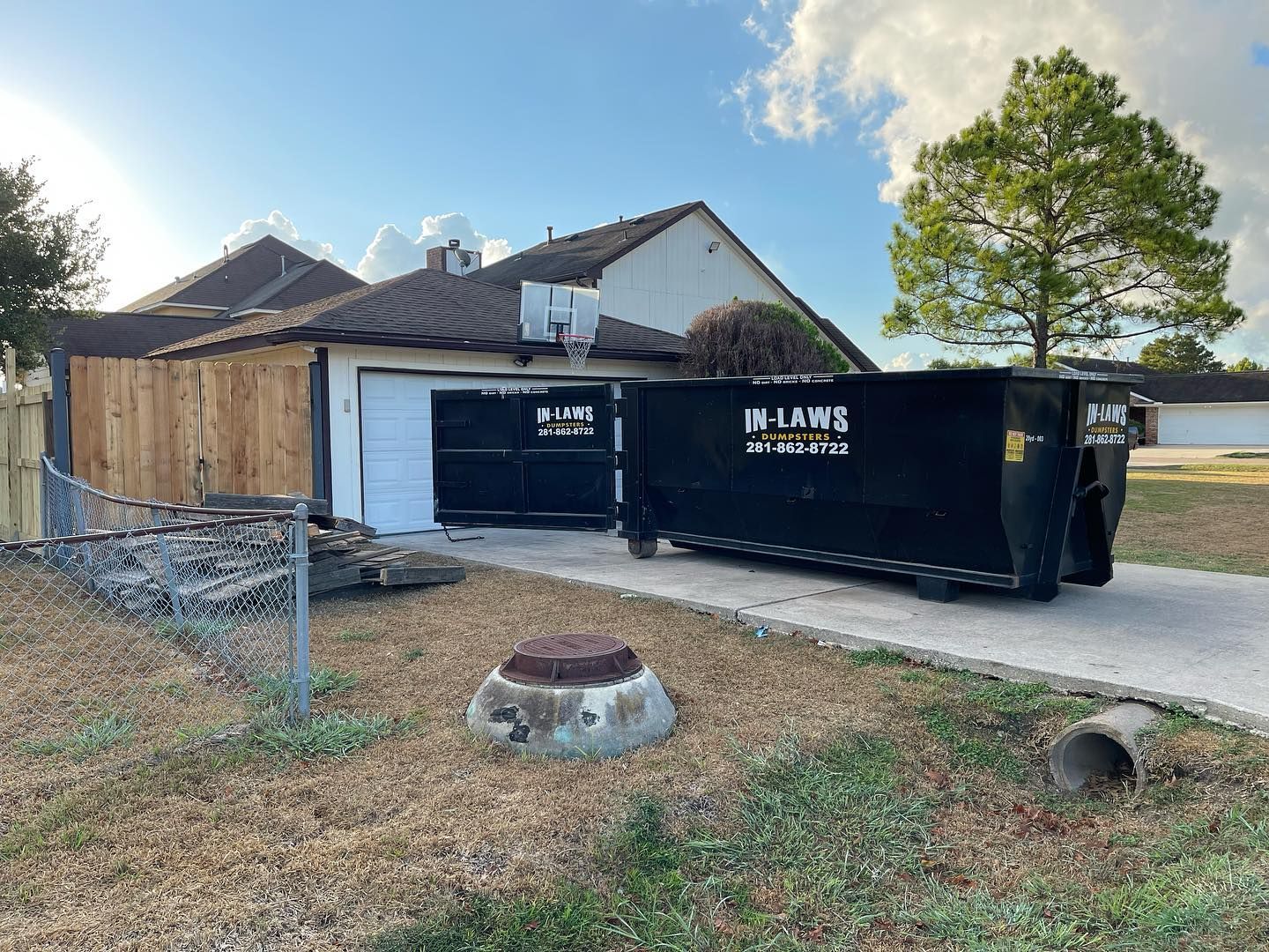 A dumpster is parked in front of a house that is being demolished.