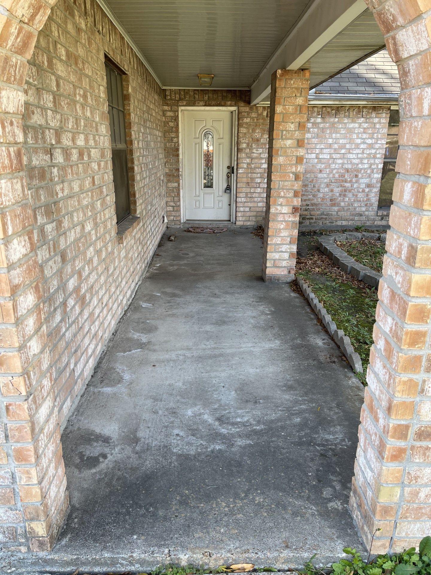 A brick house with a concrete walkway leading to the front door.