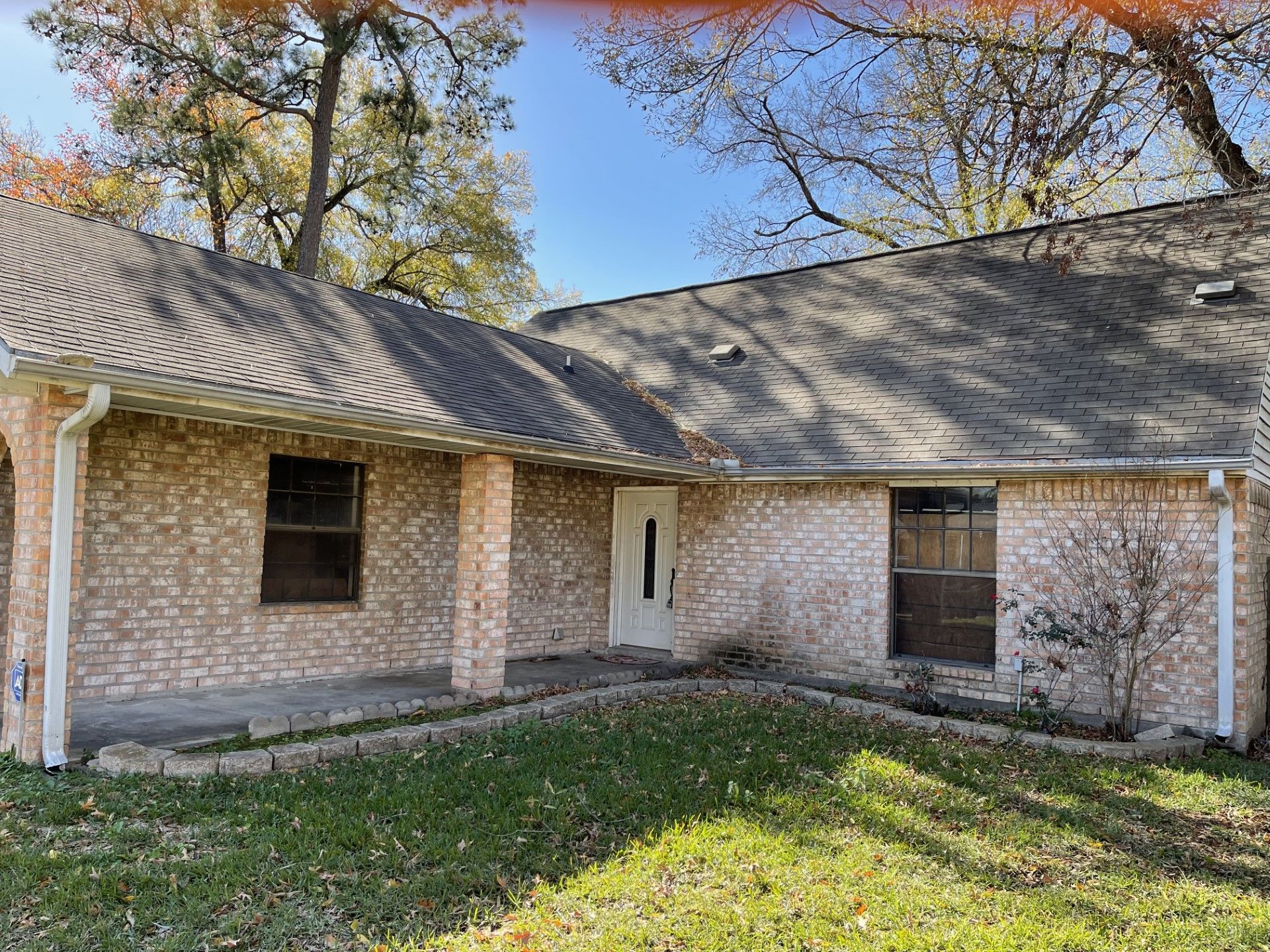 A brick house with a gray roof and a white door is for sale.