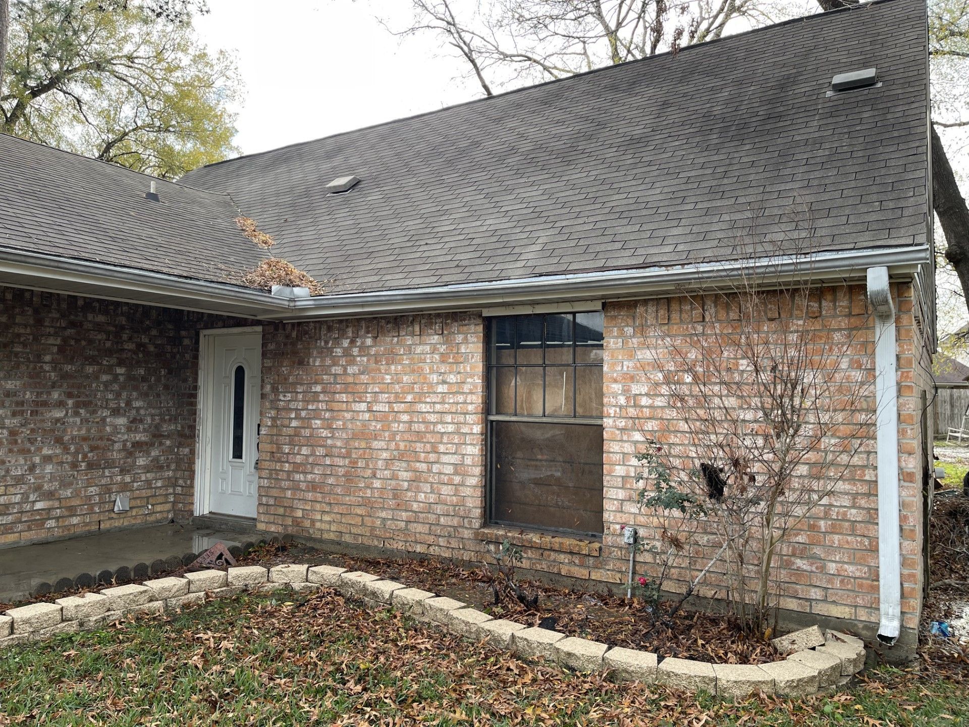 A brick house with a black roof and a white door.