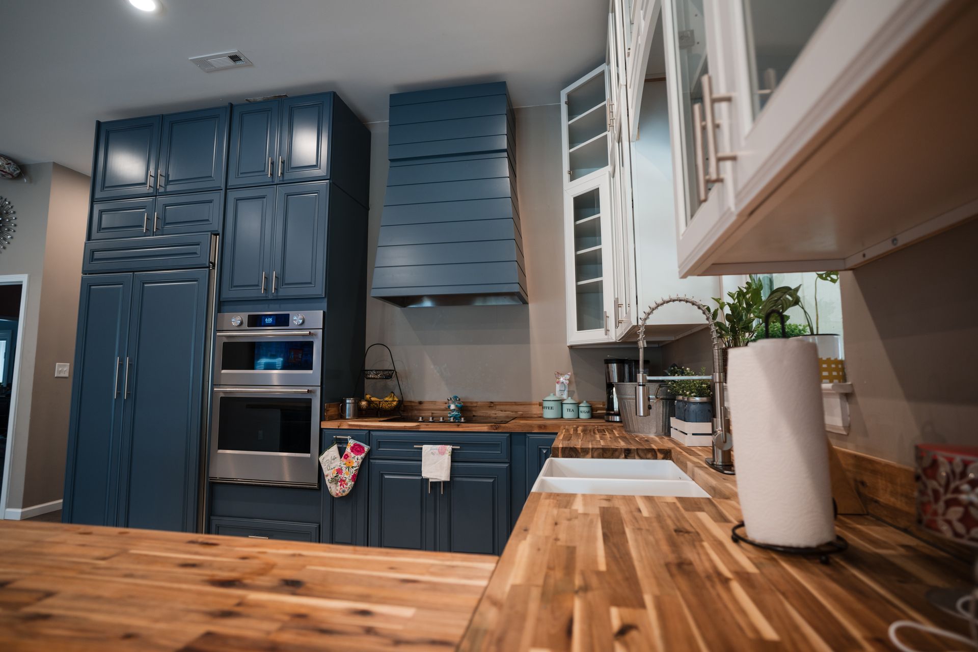 Modern kitchen with blue cabinets, wooden countertops, and a farmhouse sink
