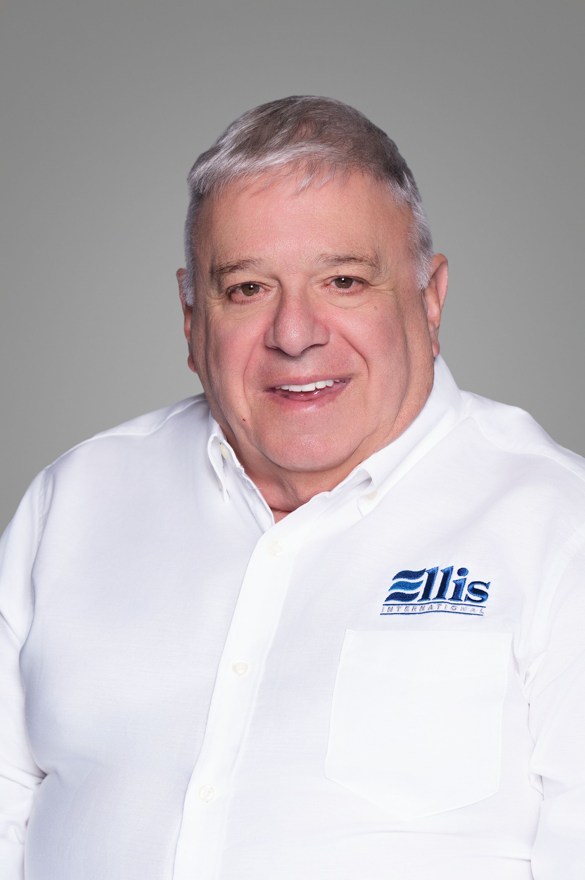Smiling woman in a white Eliis-branded shirt against a gray background