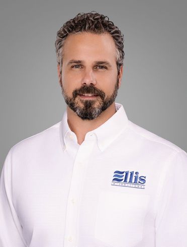 Smiling man in a white Eliis-branded shirt against a gray background