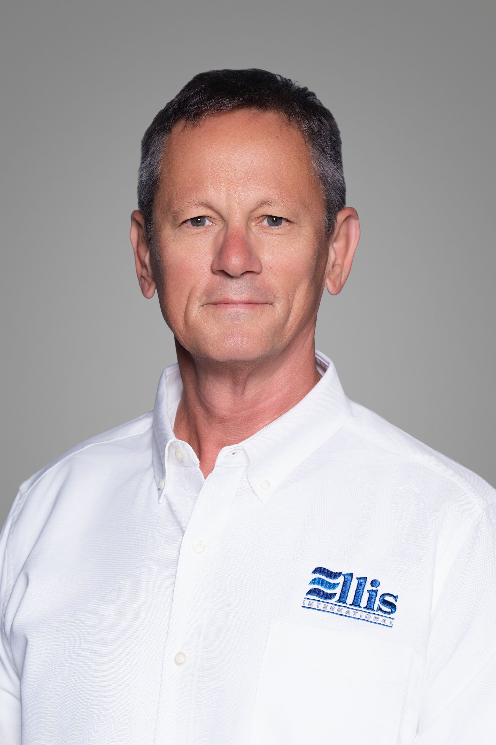 Smiling woman in a white Eliis-branded shirt against a gray background