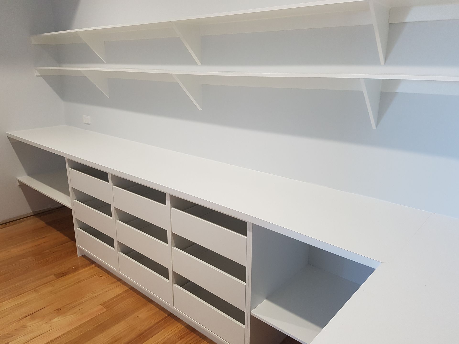 A Kitchen with Black Cabinets and Drawers and A Brick Wall — Tailored Interiors in Wacol, QLD