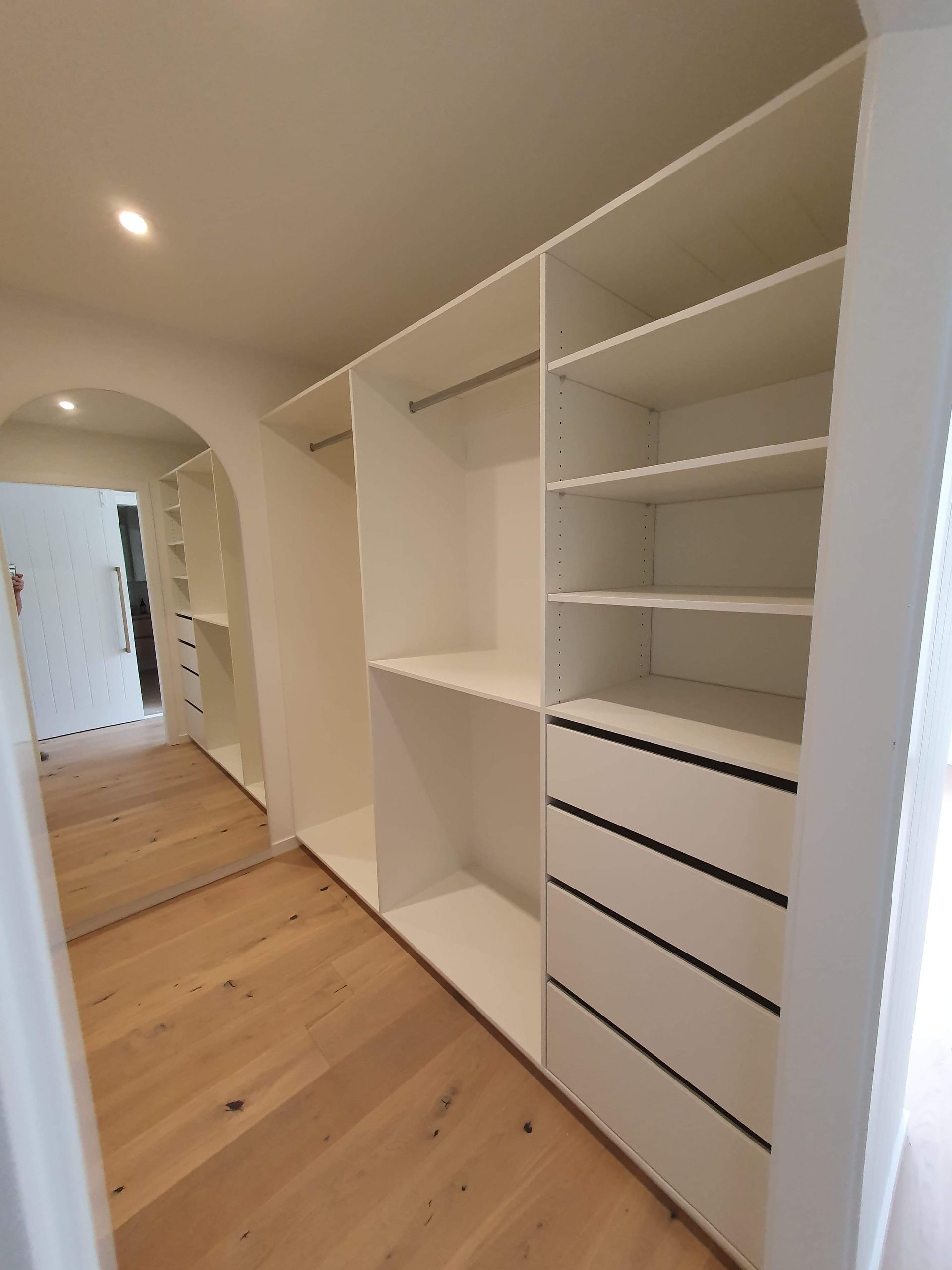 A walk in closet with lots of shelves and drawers and a mirror.