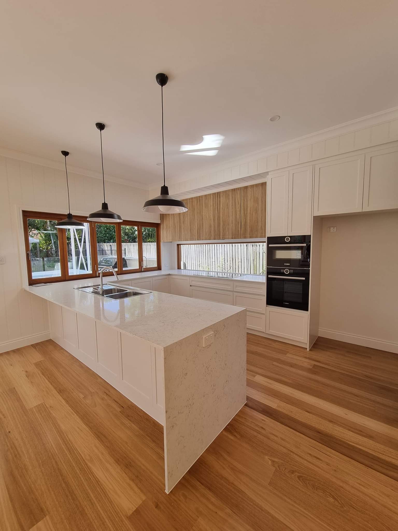A Kitchen with Stainless Steel Appliances , Granite Counter Tops , Wooden Cabinets and Hardwood Floors — Tailored Interiors in Wacol, QLD
