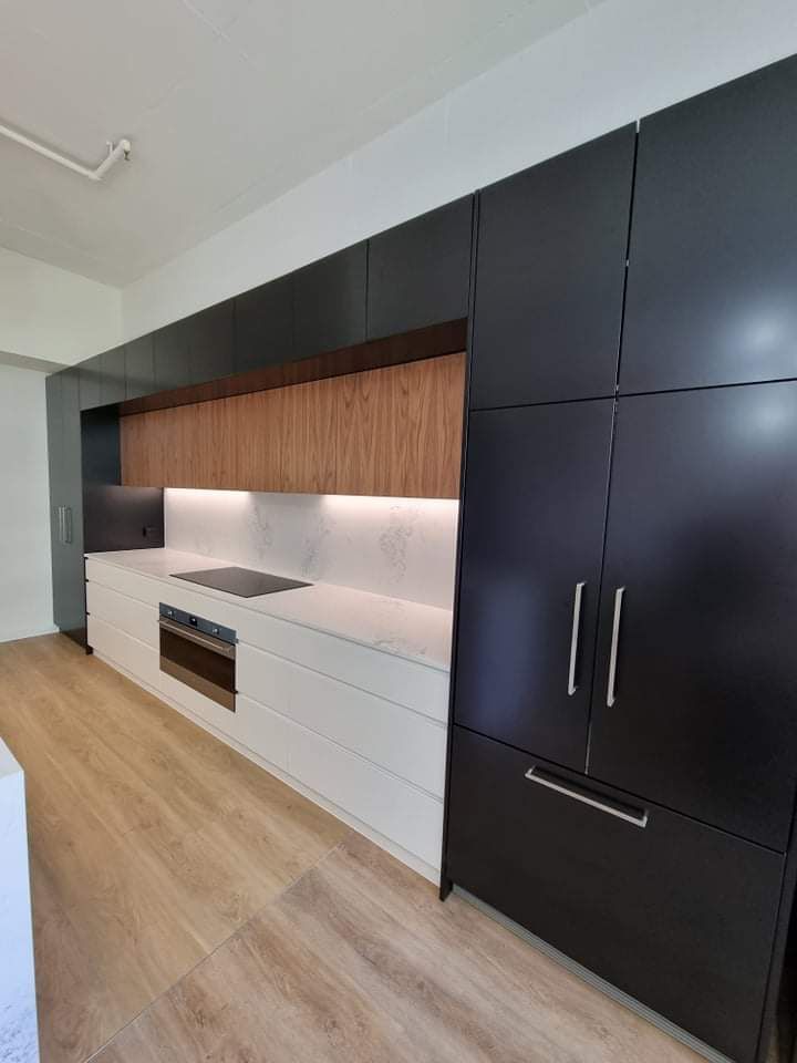 A kitchen with black cabinets and white counter tops.