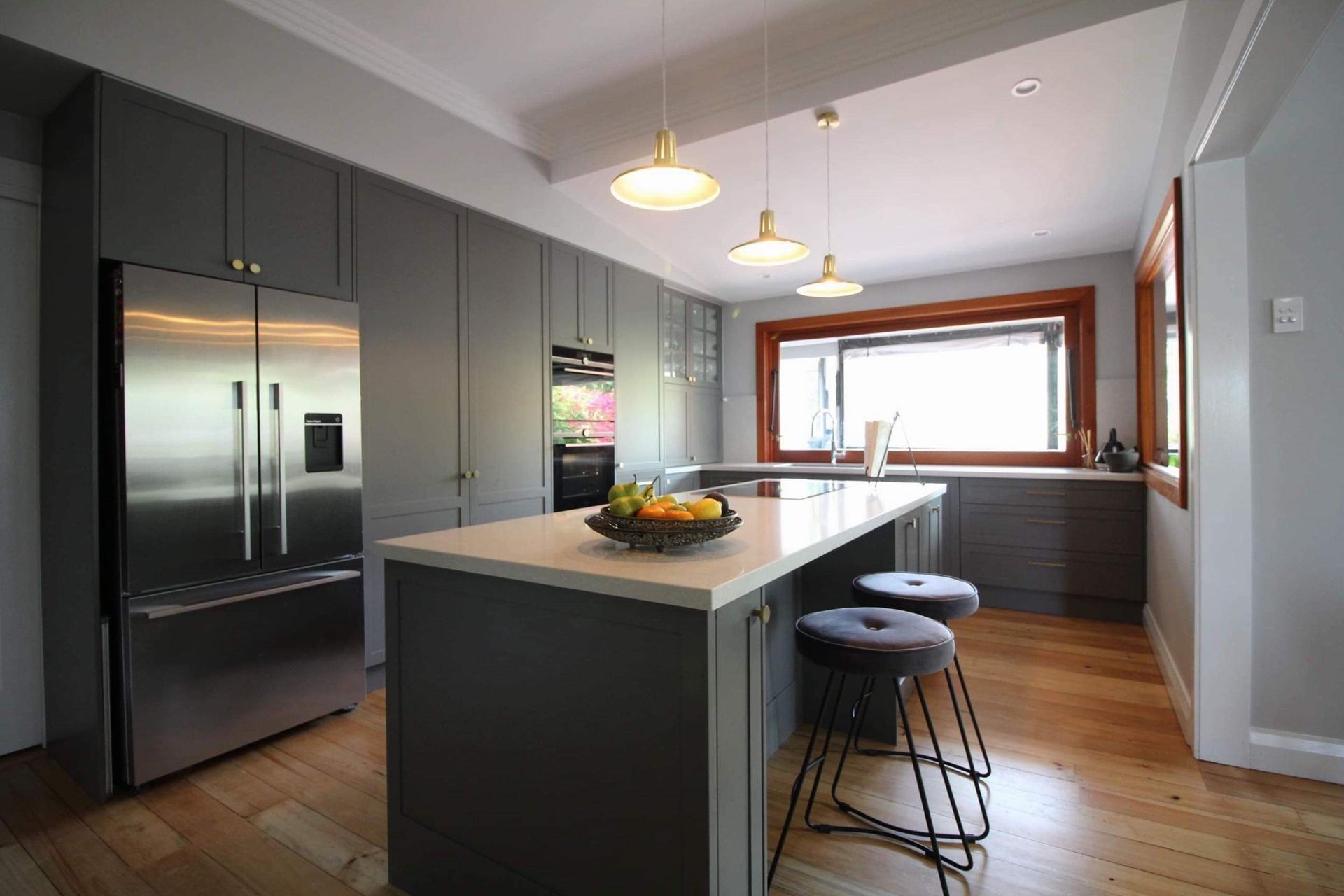 A kitchen with stainless steel appliances and a large island with a bowl of fruit on it.