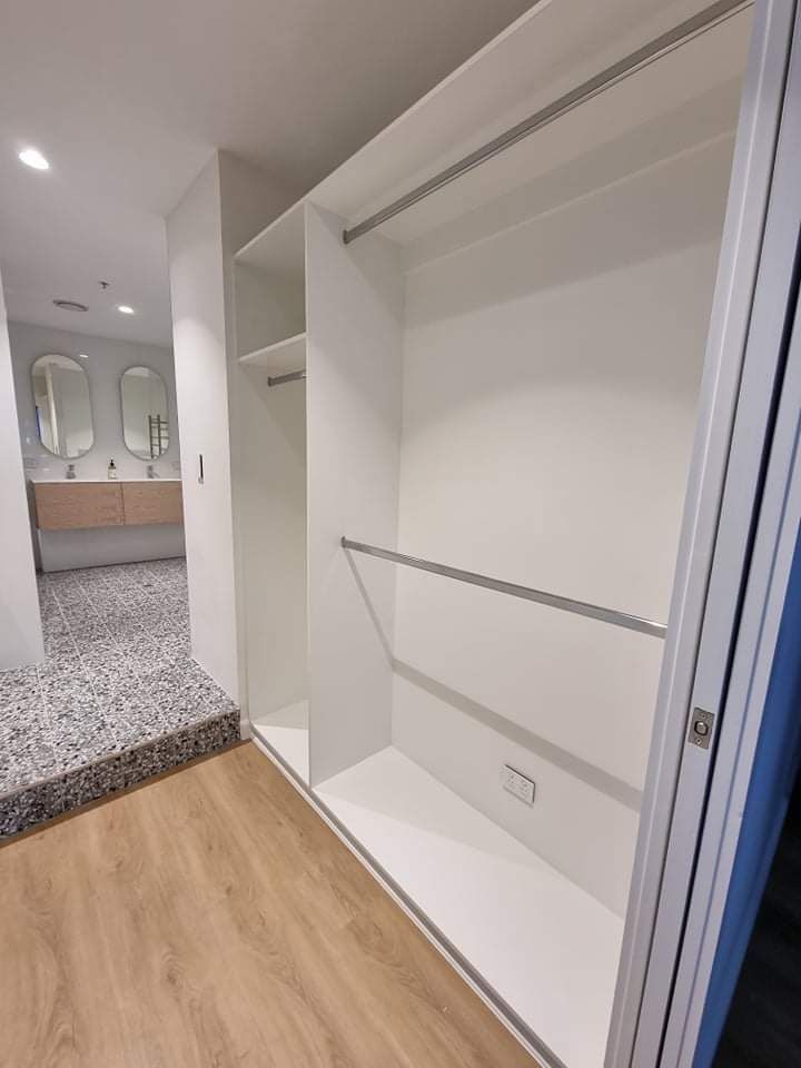 A Modern Kitchen with White Cabinets , Granite Counter Tops , Stainless Steel Appliances , and A Large Island — Tailored Interiors in Cleveland, QLD