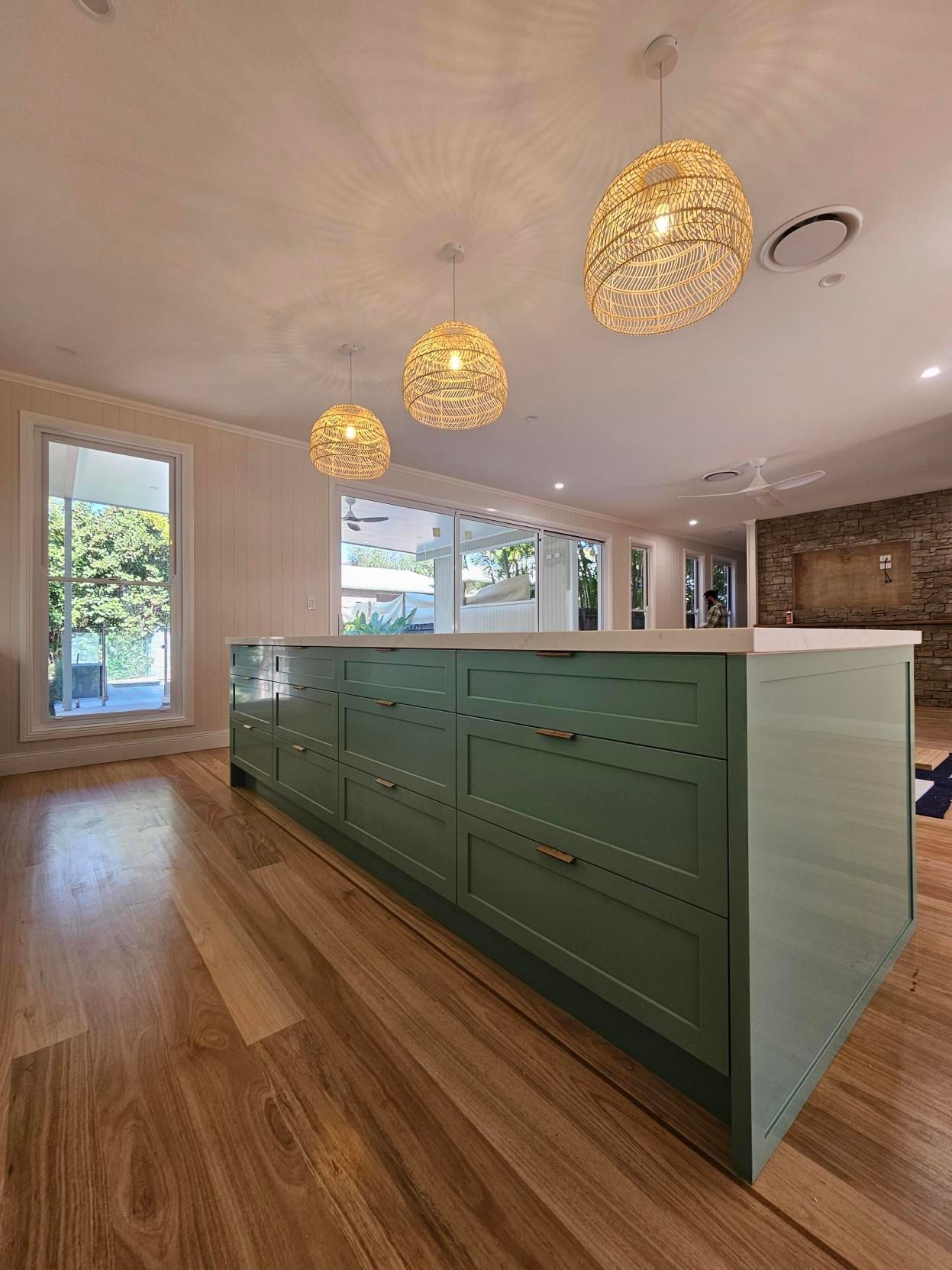 A kitchen with green cabinets and a large island in the middle of the room.