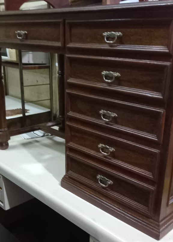 Un escritorio de madera con un único cajón superior y una pila vertical de cinco cajones, con tiradores tradicionales