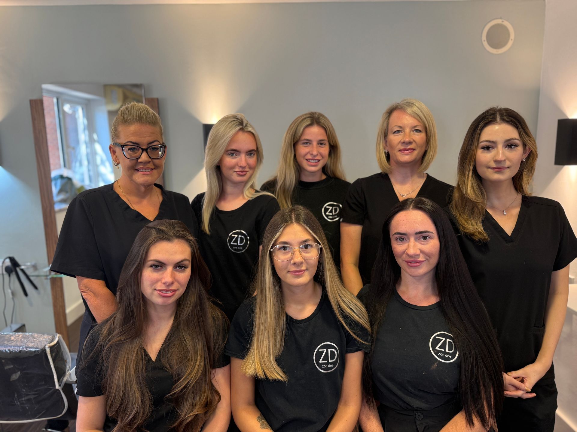 The team at Zoe Dee are posing for a picture in a salon.