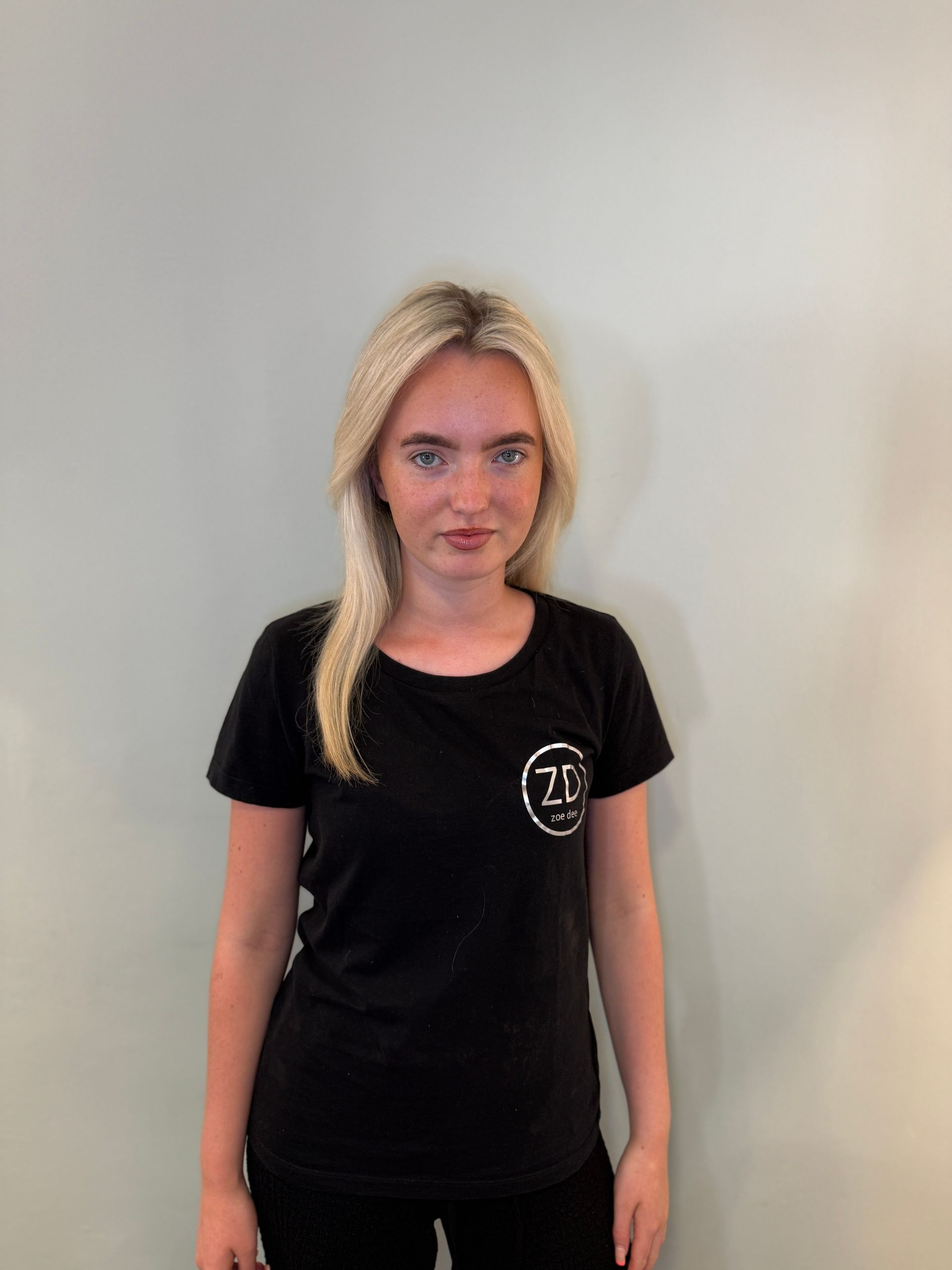 Daisy is wearing a black sweater with a Zoe Dee logo on it.