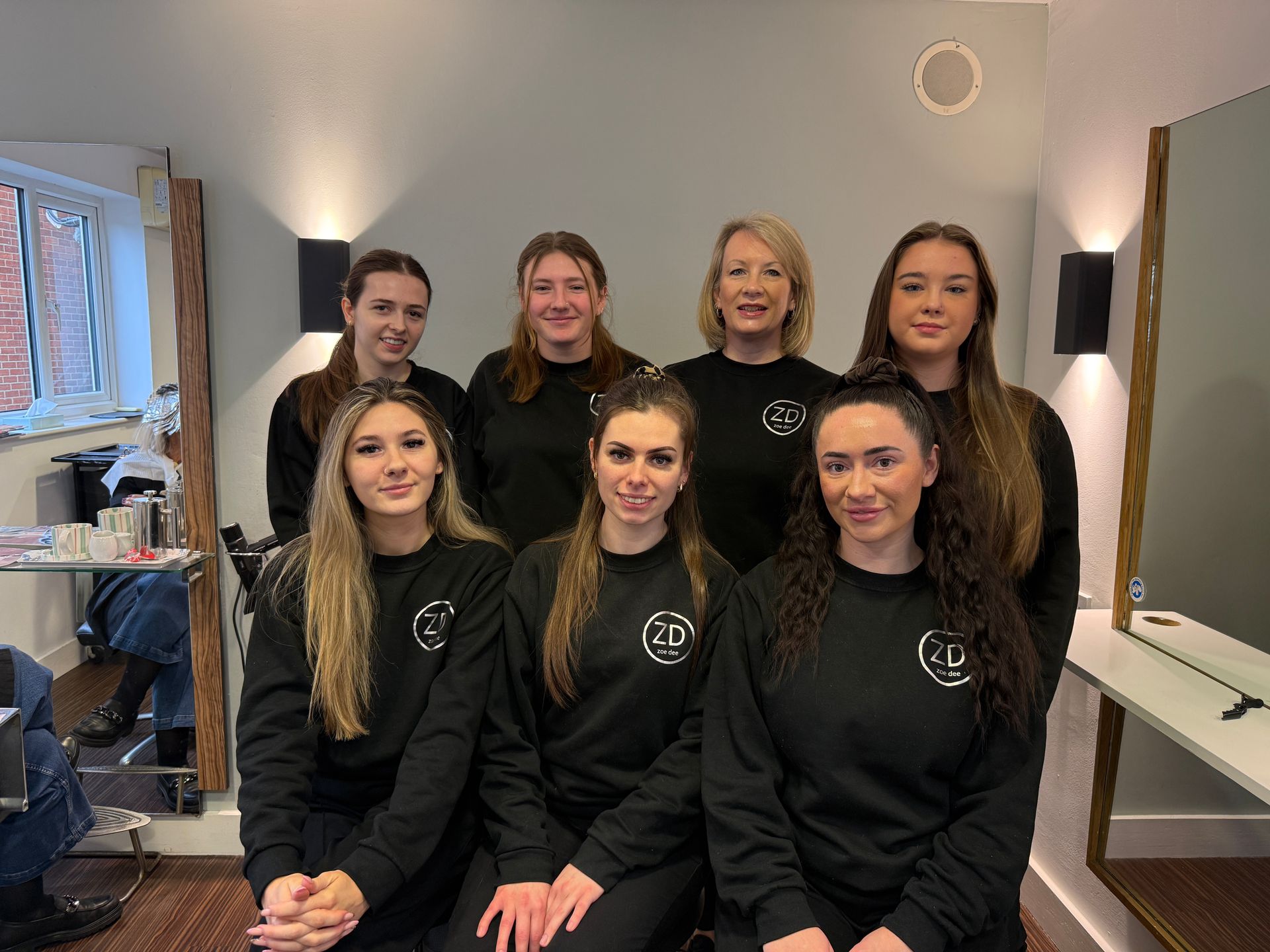The team at Zoe Dee are posing for a picture in a salon.
