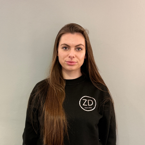 Stacia is a woman with long hair is wearing a black logo'd Zoe Dee sweatshirt.