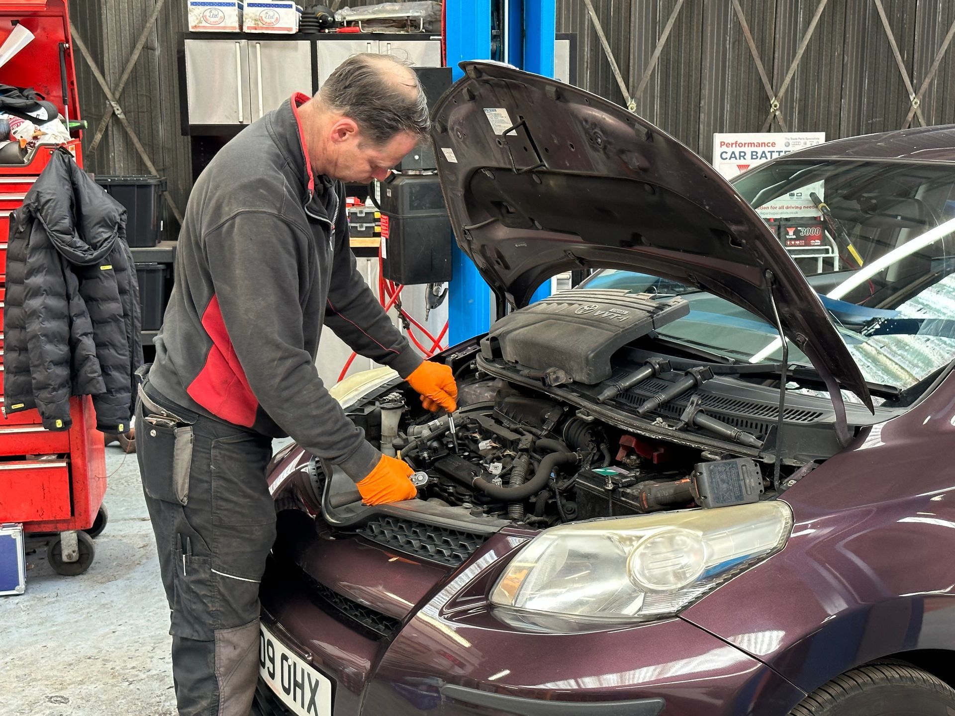 A man is working on the engine of a car in a garage.