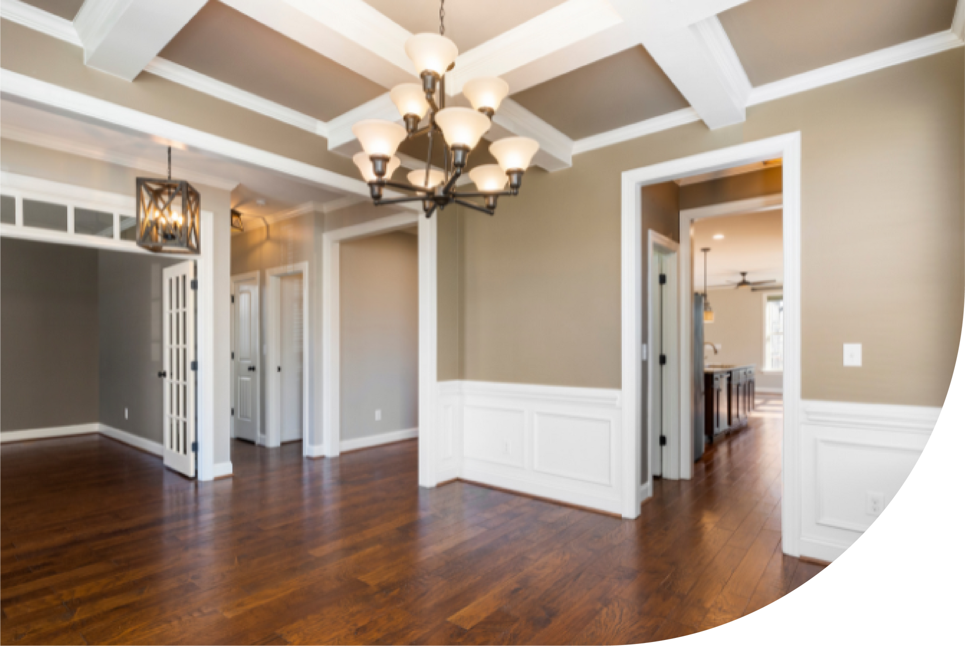 An empty room with hardwood floors and a chandelier hanging from the ceiling.