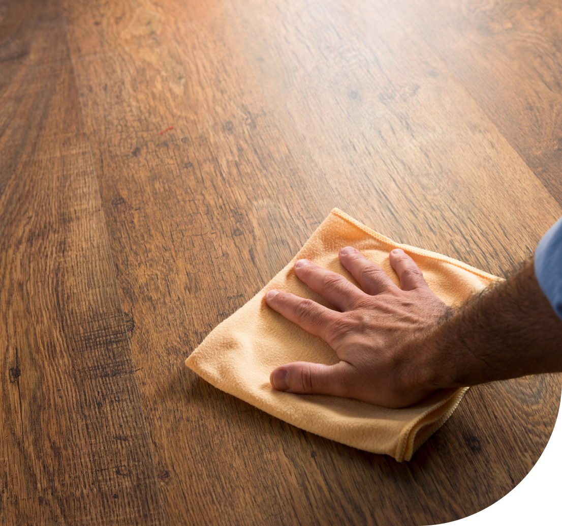 A homeowner wiping wooden floors with wax
