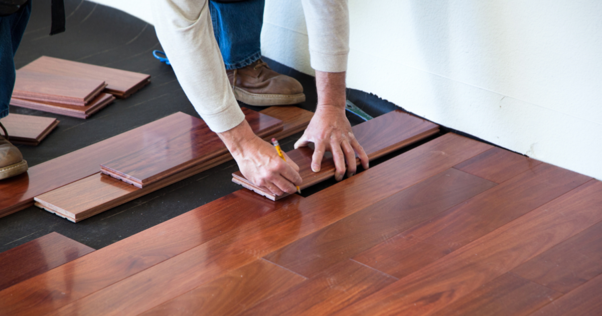 A professional installing hardwood floor planks