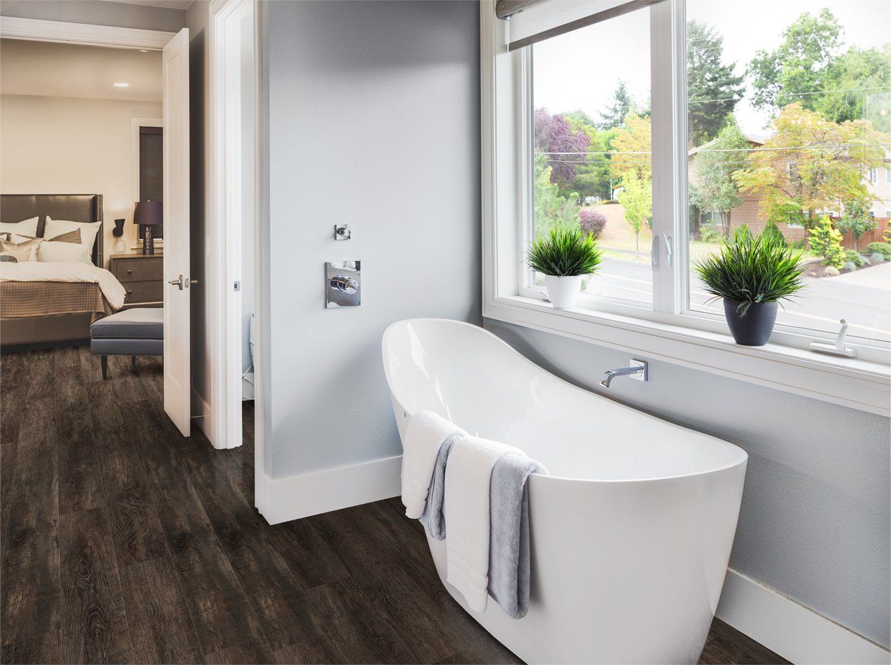 A well-designed home bathroom with a tub with Cali Shadowed Oak Luxury Vinyl Flooring